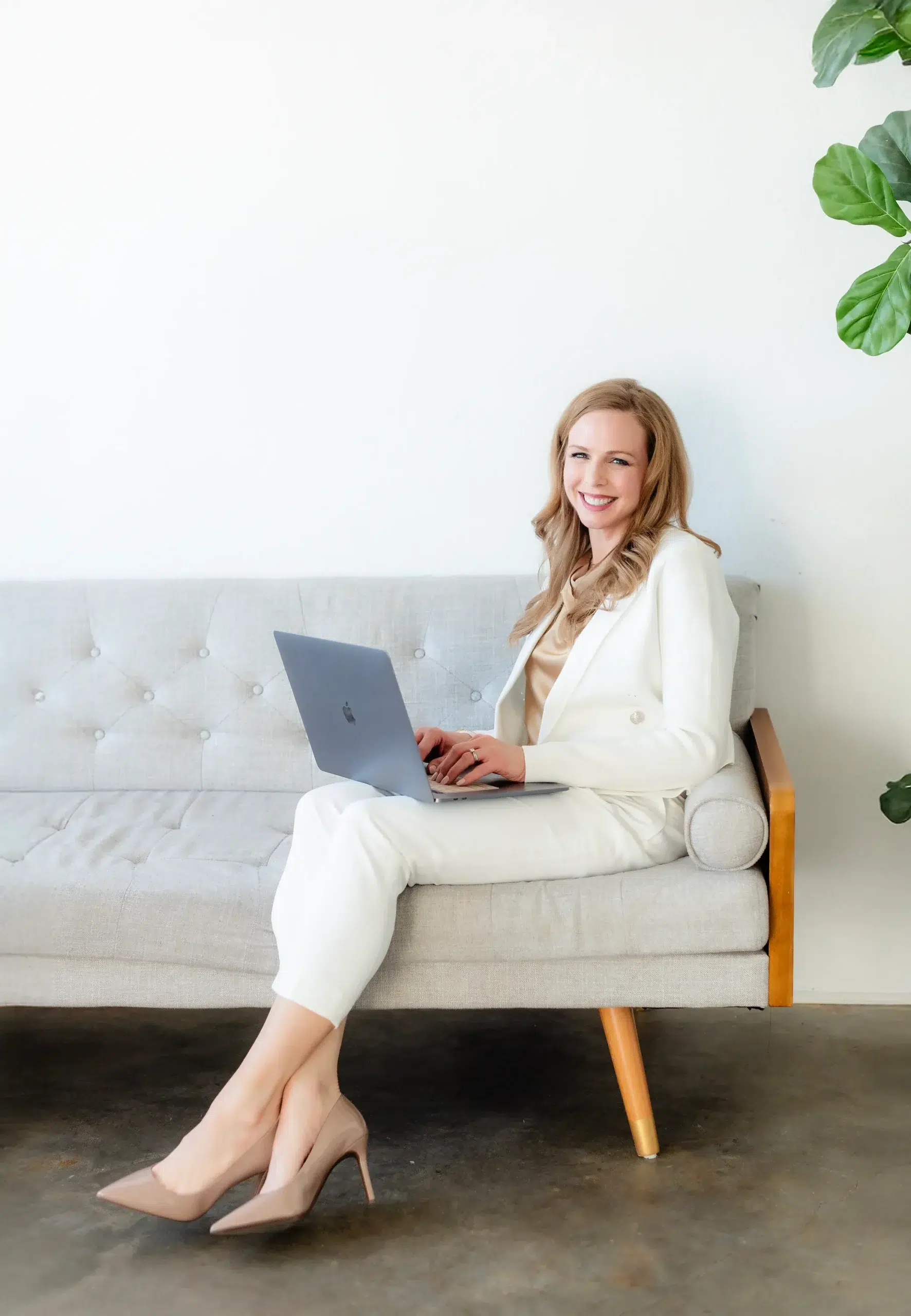 Heather Siegel working on web design, sitting on a couch with her computer and wearing a white suit. She is getting ready to share her why behind web design